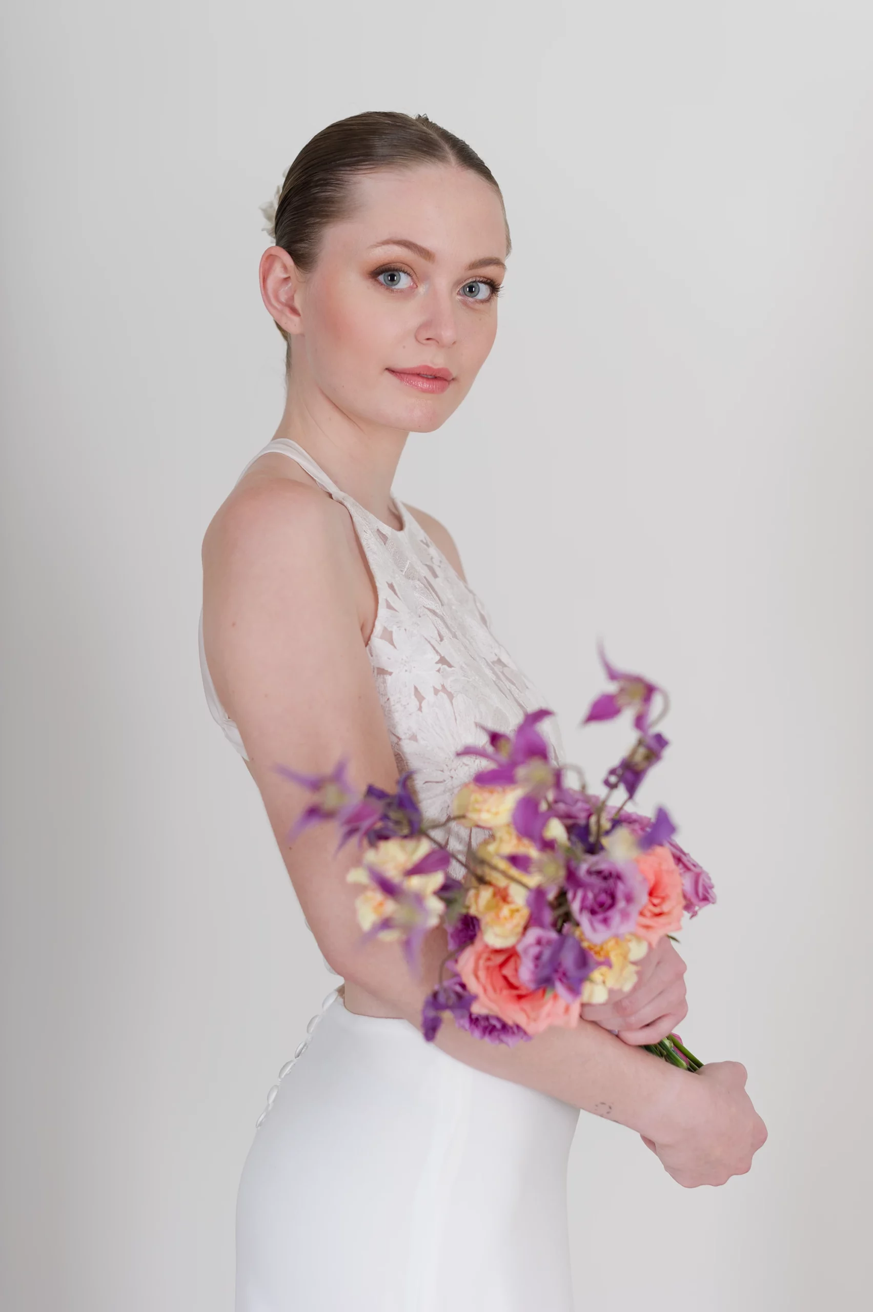 Mariée en robe dos nu tenant un bouquet coloré de fleurs fraîches.