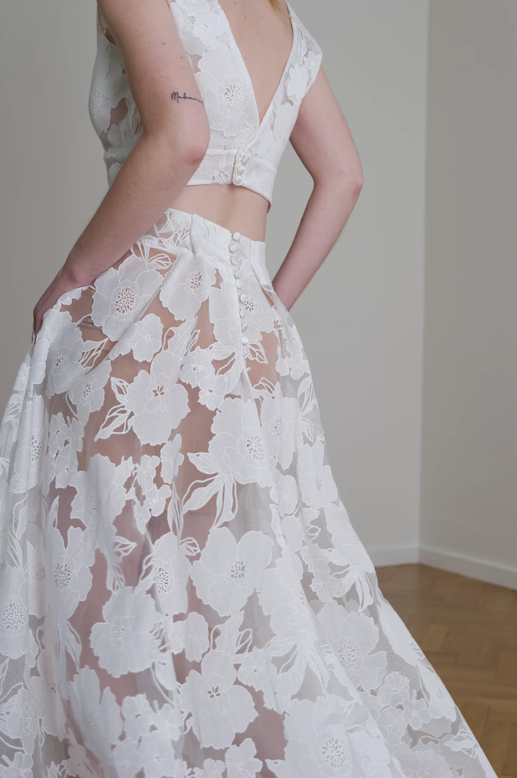 Détail d'une robe de mariée deux pièces en dentelle florale avec boutons sur le dos.