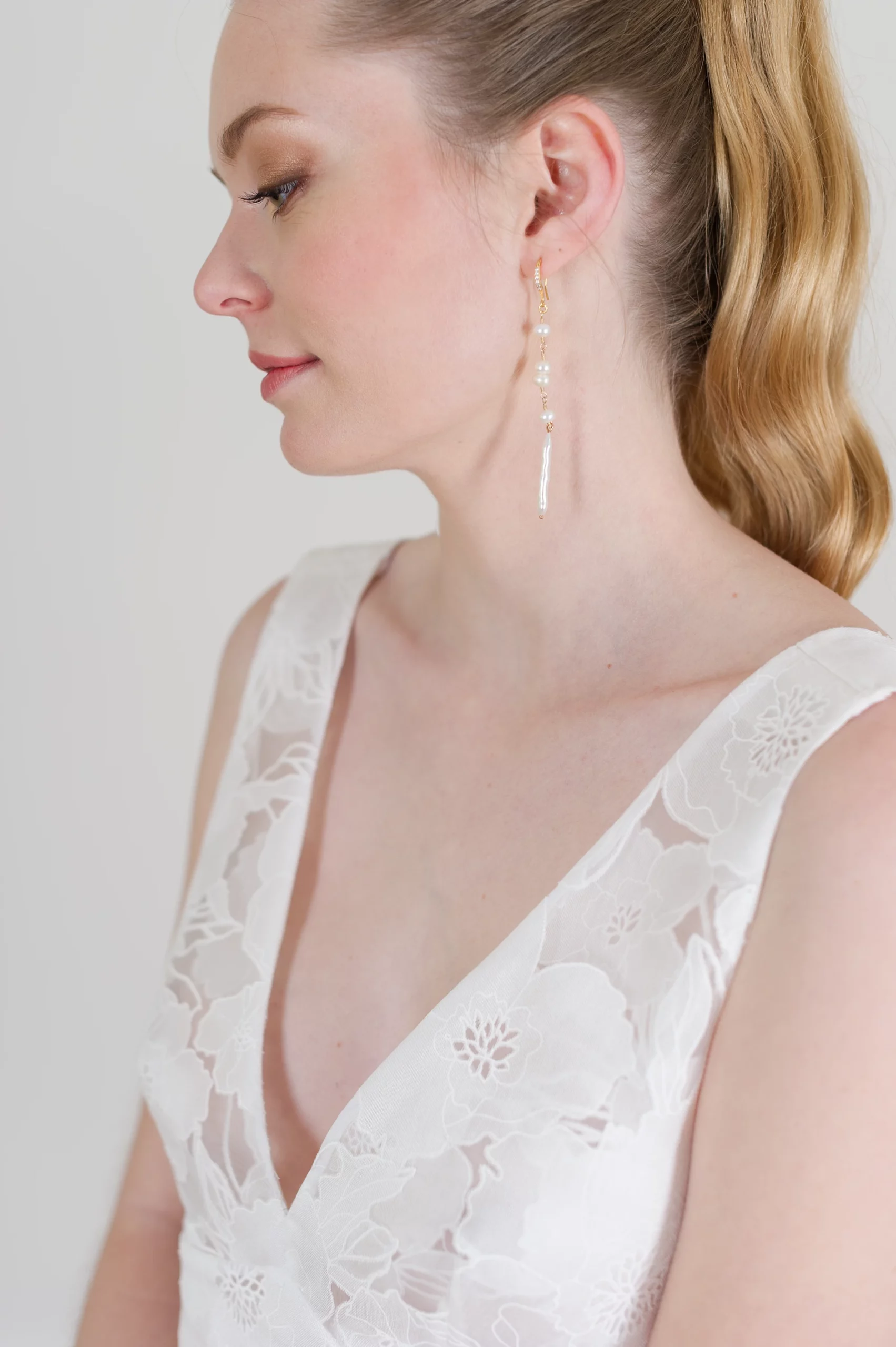 Profil de mariée avec robe en dentelle florale et boucles d'oreilles pendantes élégantes.