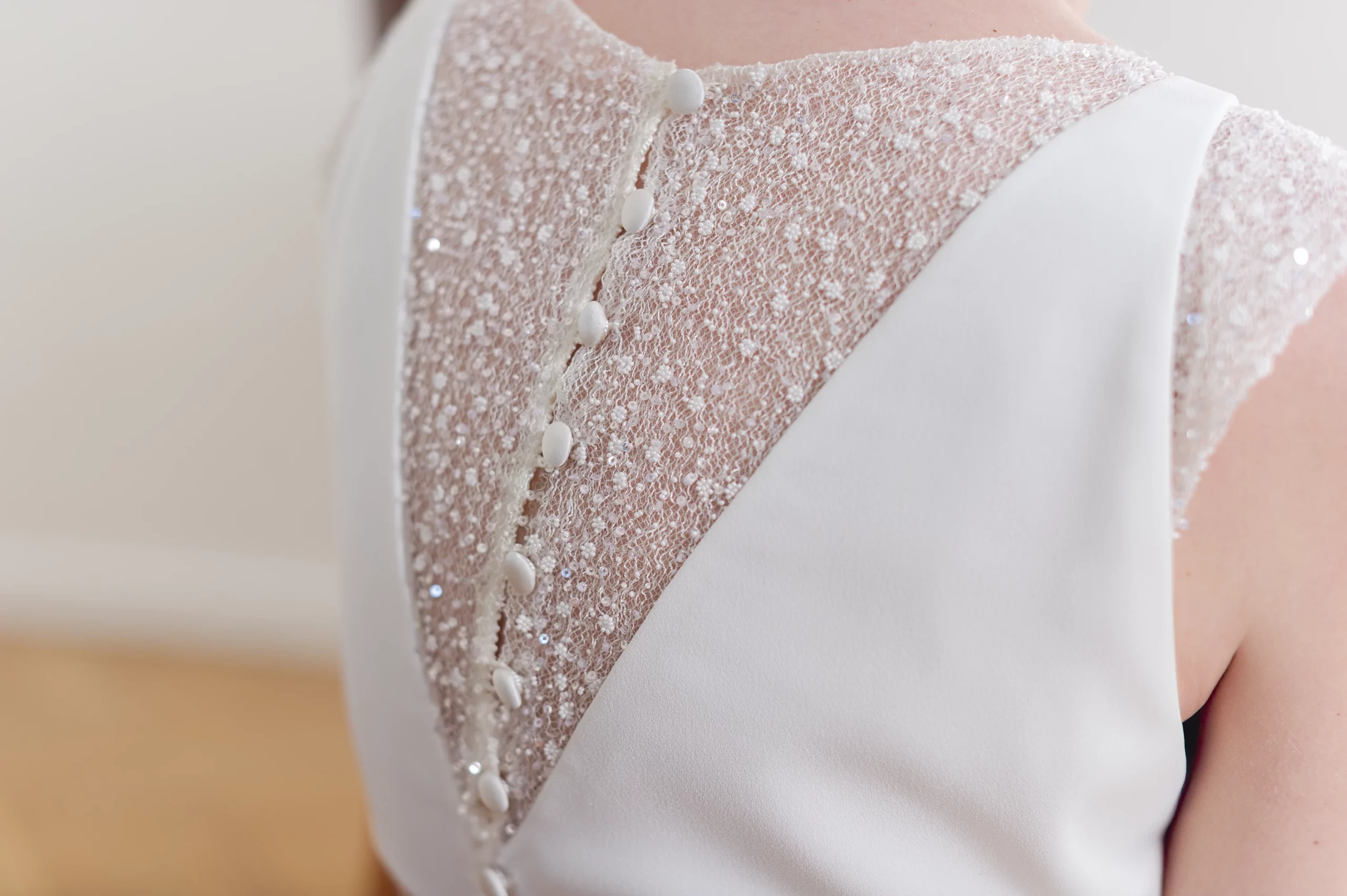 Détail du dos en dentelle scintillante avec boutons sur une robe de mariée.