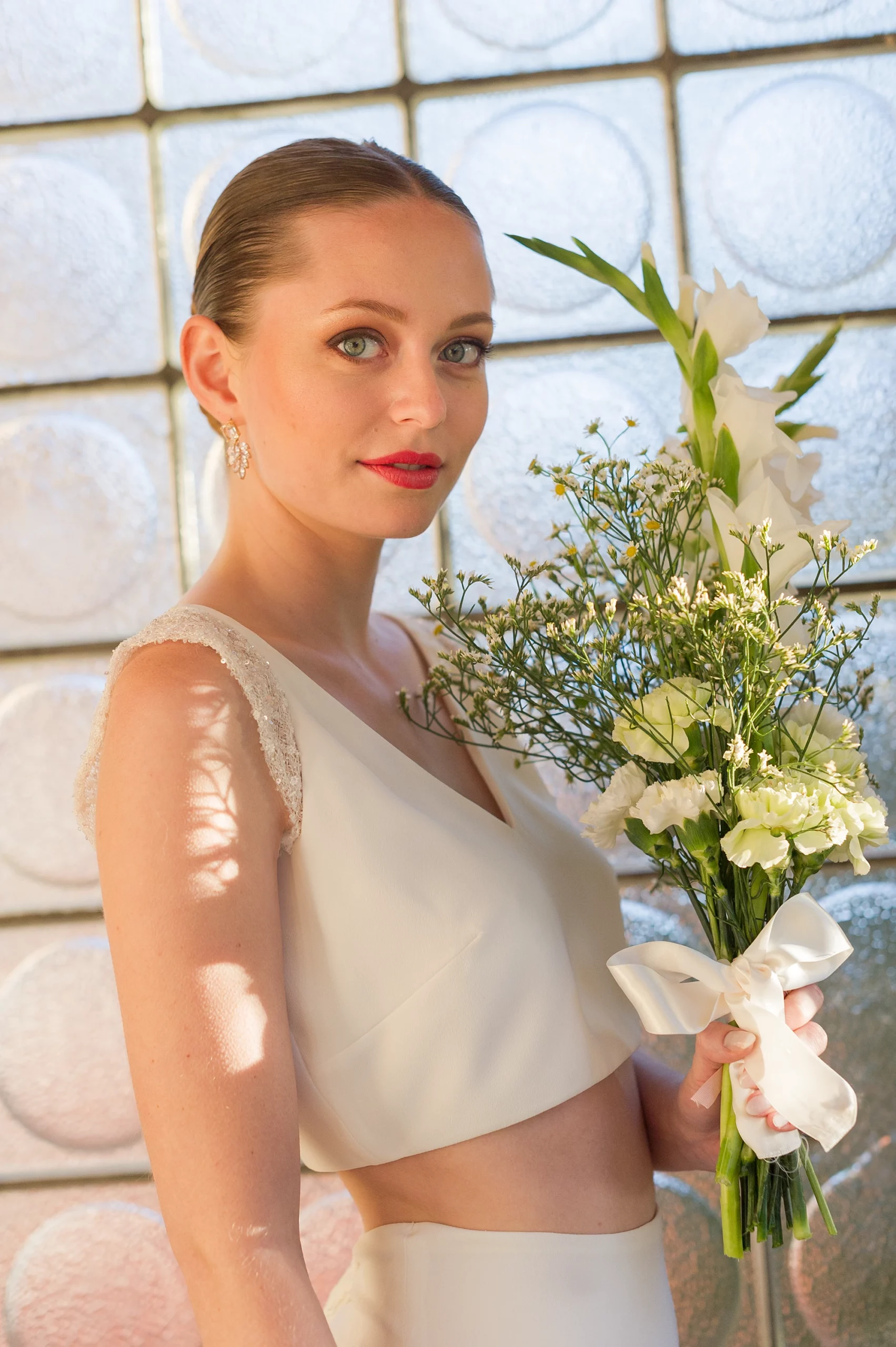 Mariée avec bouquet de fleurs blanches, portant une robe deux pièces élégante.