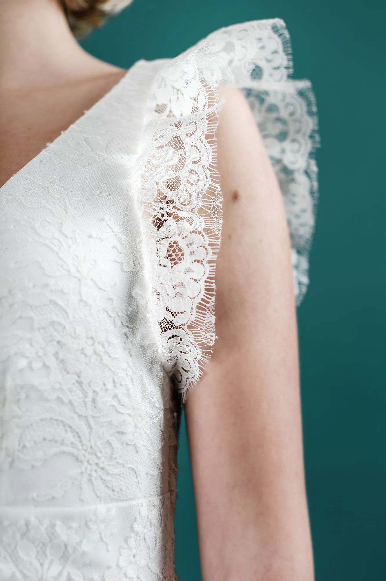 Détail de la manche en dentelle de la robe de mariée 'Hannah', montrant la texture délicate et les bords fins de la dentelle florale.