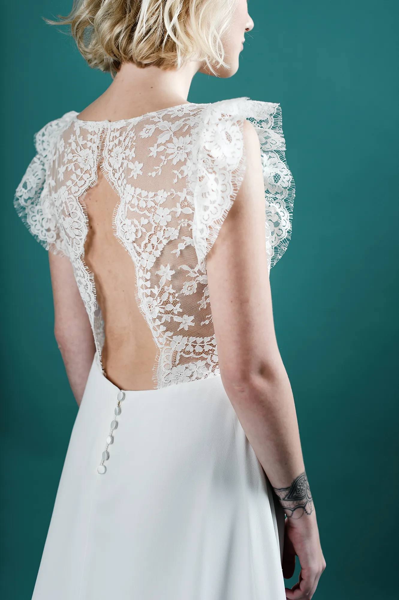 Robe de mariée "Hannah" en crêpe de soie avec manches en dentelle florale, dos nu et boutons délicats.