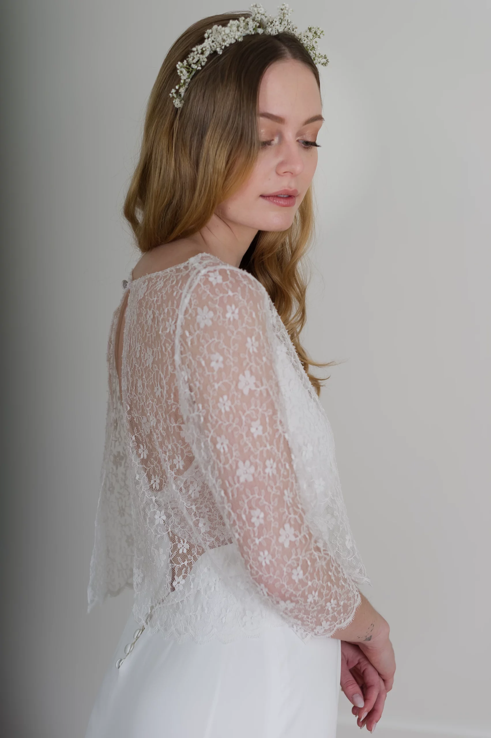 Vue latérale de la robe de mariée en dentelle avec couronne de gypsophile et manches longues