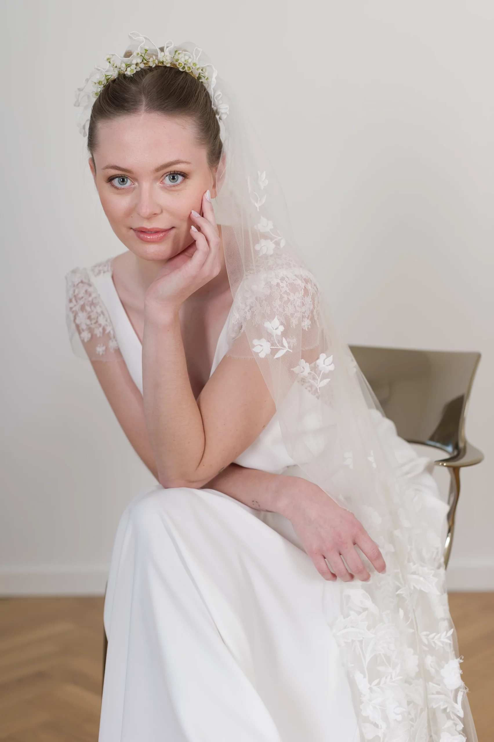 Mariée avec la robe de mariée Virginia, ornée de manches en dentelle florale et accompagnée d'un voile délicatement décoré.