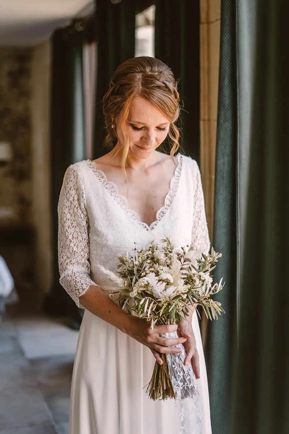 Pauline - Robe de mariée en Dentelle de Calais – Création sur mesure Louise Dentelle à Toulouse Mariée portant une robe Louise Dentelle en Dentelle de Calais, manches trois-quarts et jupe fluide, bouquet de fleurs séchées à la main, lumière naturelle à Toulouse.