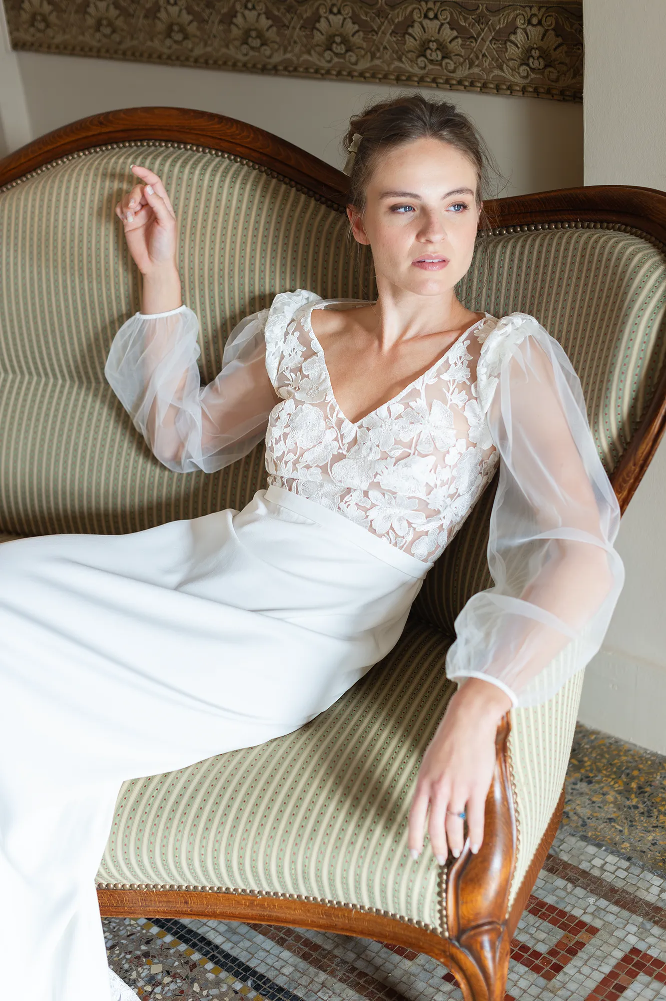 Robe de mariée Alma en position assise, buste brodé à décolleté V et manches longues en tulle léger. Création Louise Dentelle.