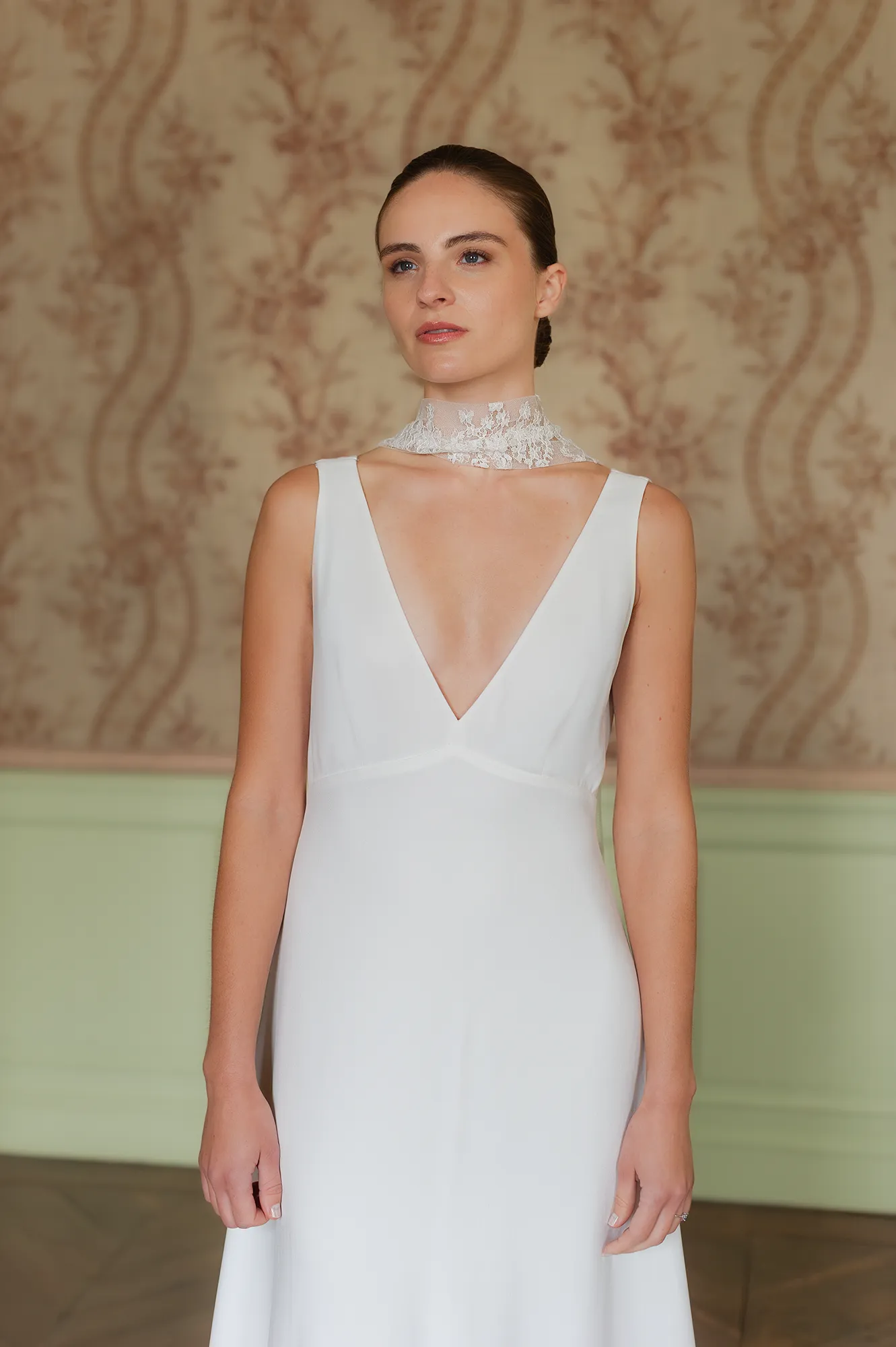 Robe de mariée Cristina au décolleté en V, portée avec une élégante écharpe en dentelle. Création Louise Dentelle.