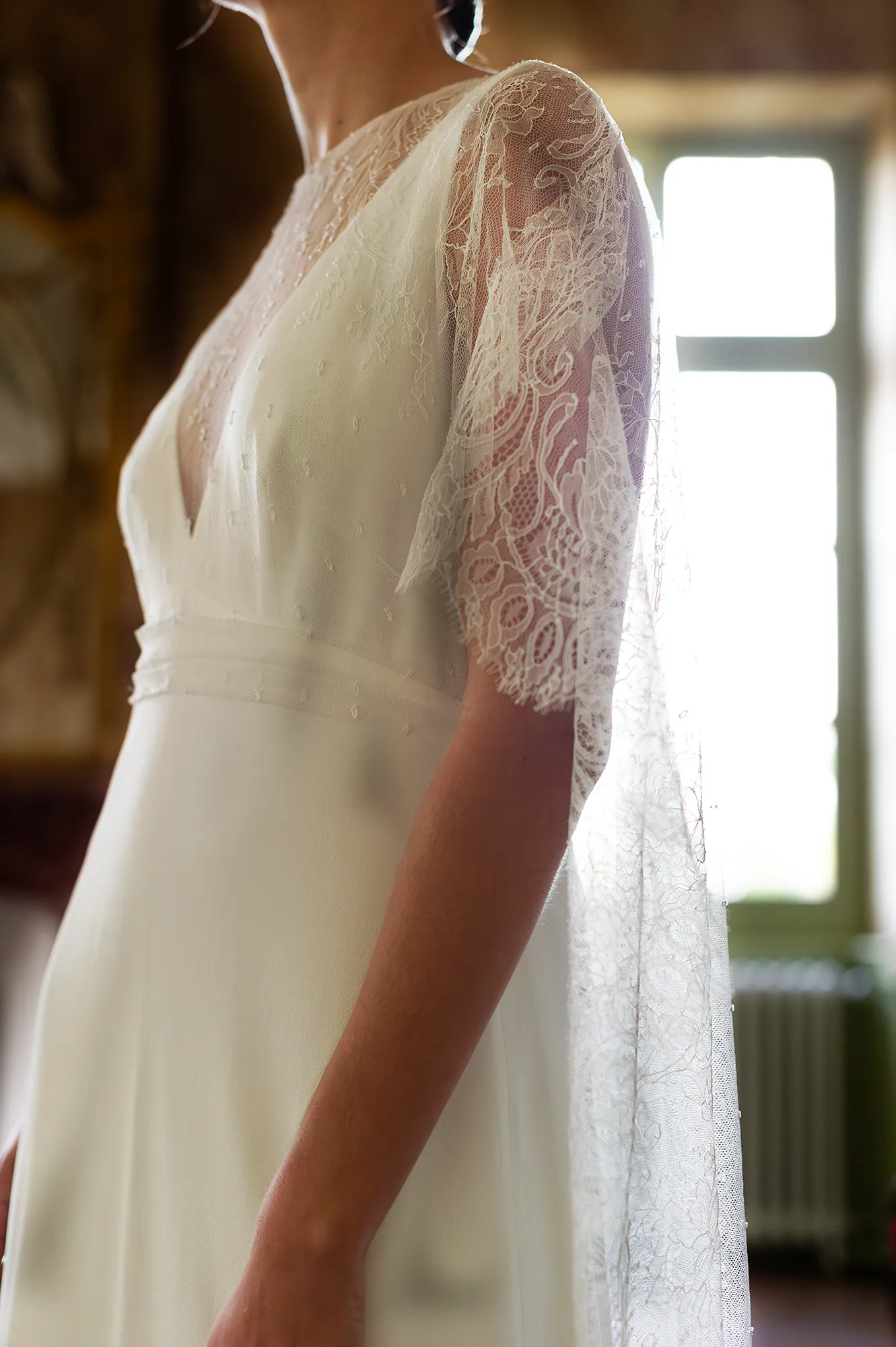 Détail du modèle Iria avec décolleté en V et manches cape en dentelle. Création Louise Dentelle à Toulouse.