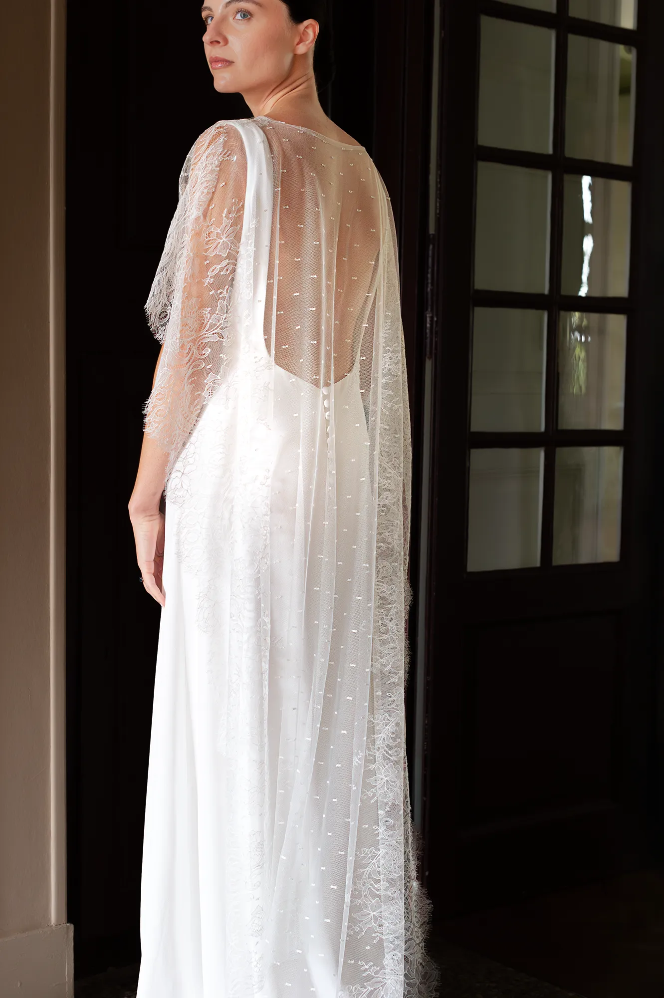 Modèle Iria vu de dos, cape en tulle brodé transparente et rangée de boutons recouverts. Création Louise Dentelle à Toulouse.