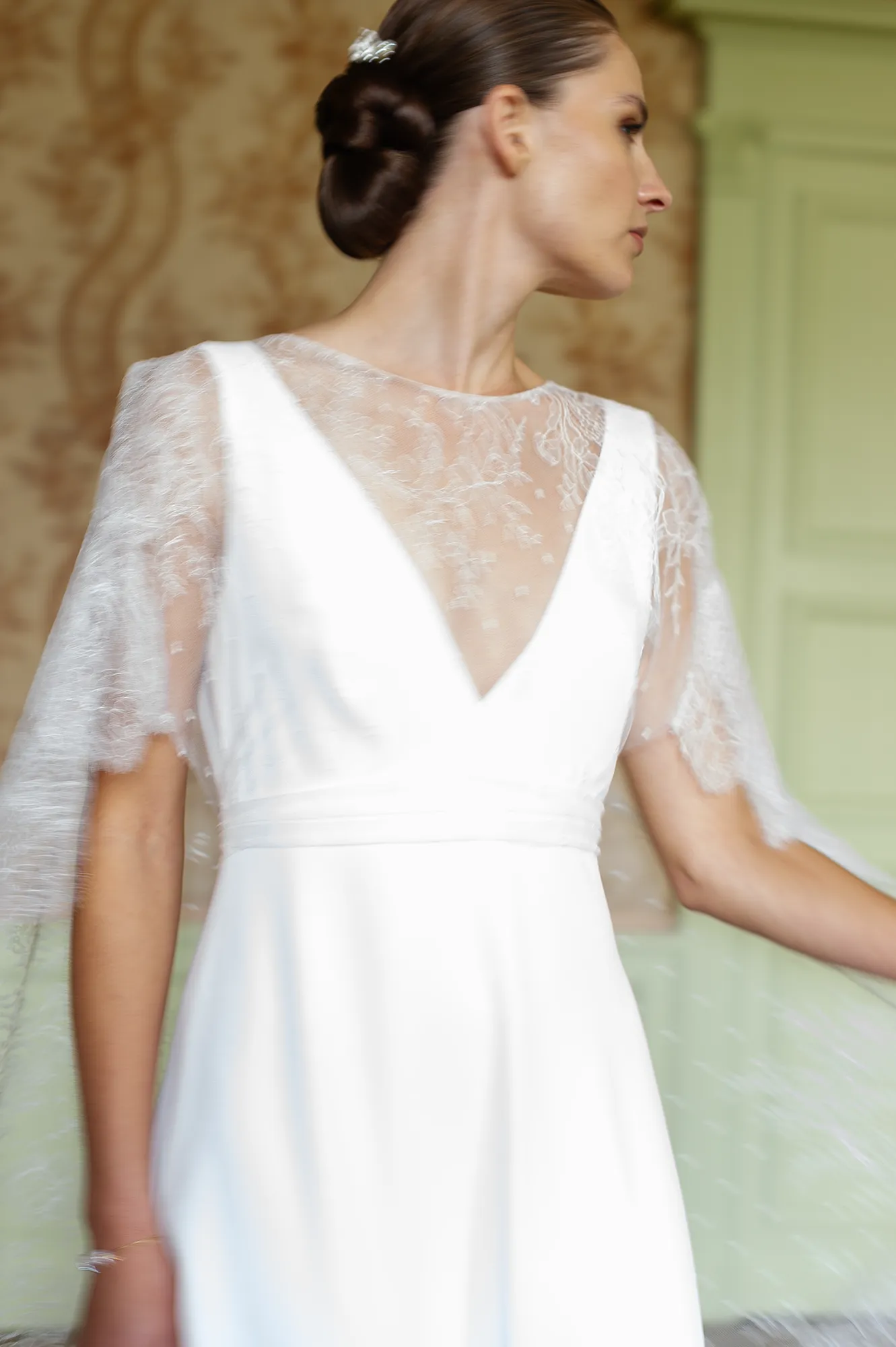 Robe de mariée Iria en mouvement, avec cape en dentelle brodée et décolleté en V. Création Louise Dentelle.