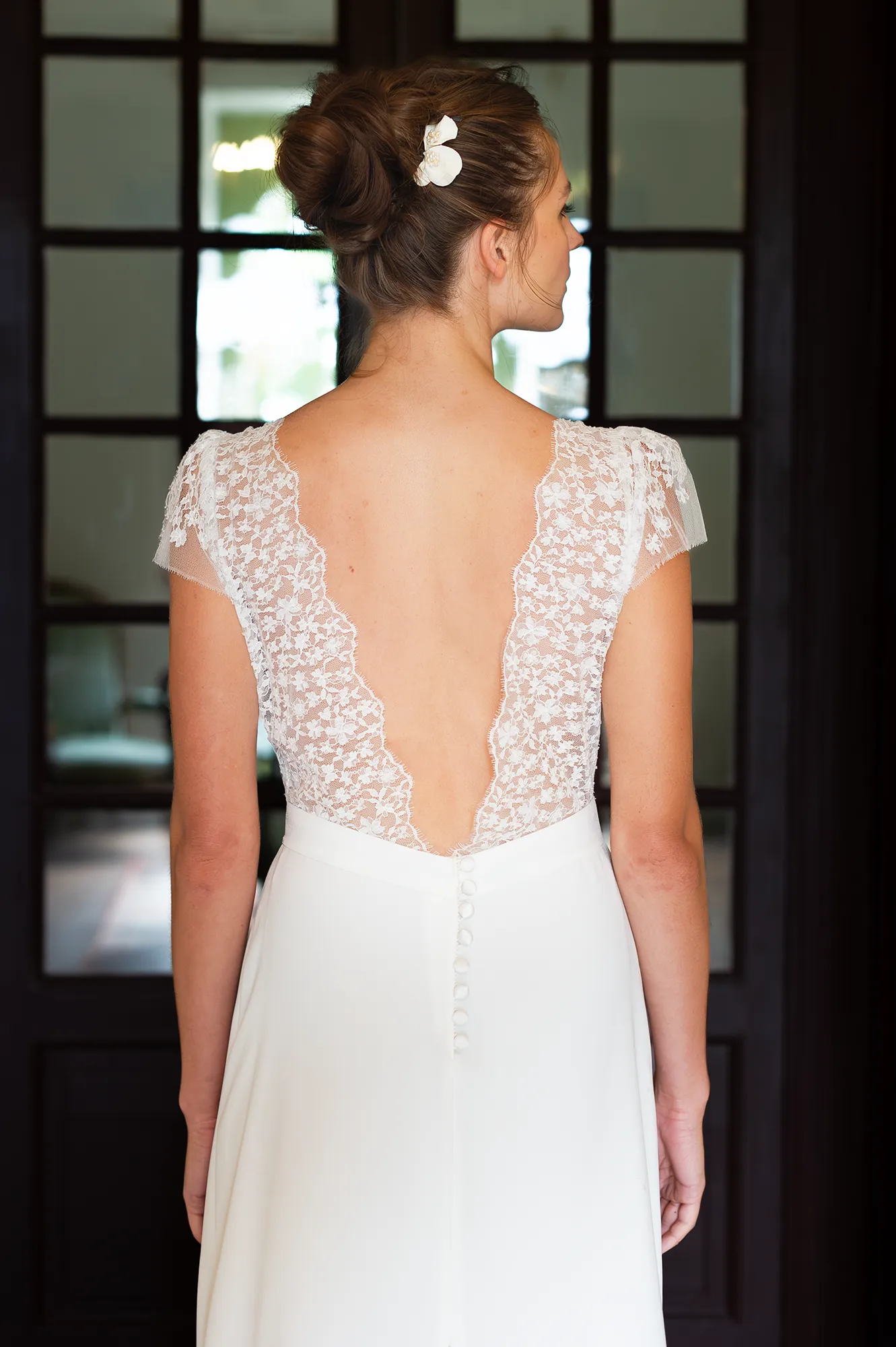 robes de mariée Rebecca vue de dos, décolleté plongeant en dentelle de Calais-Caudry et boutons recouverts. Création Louise Dentelle. robes de mariée
