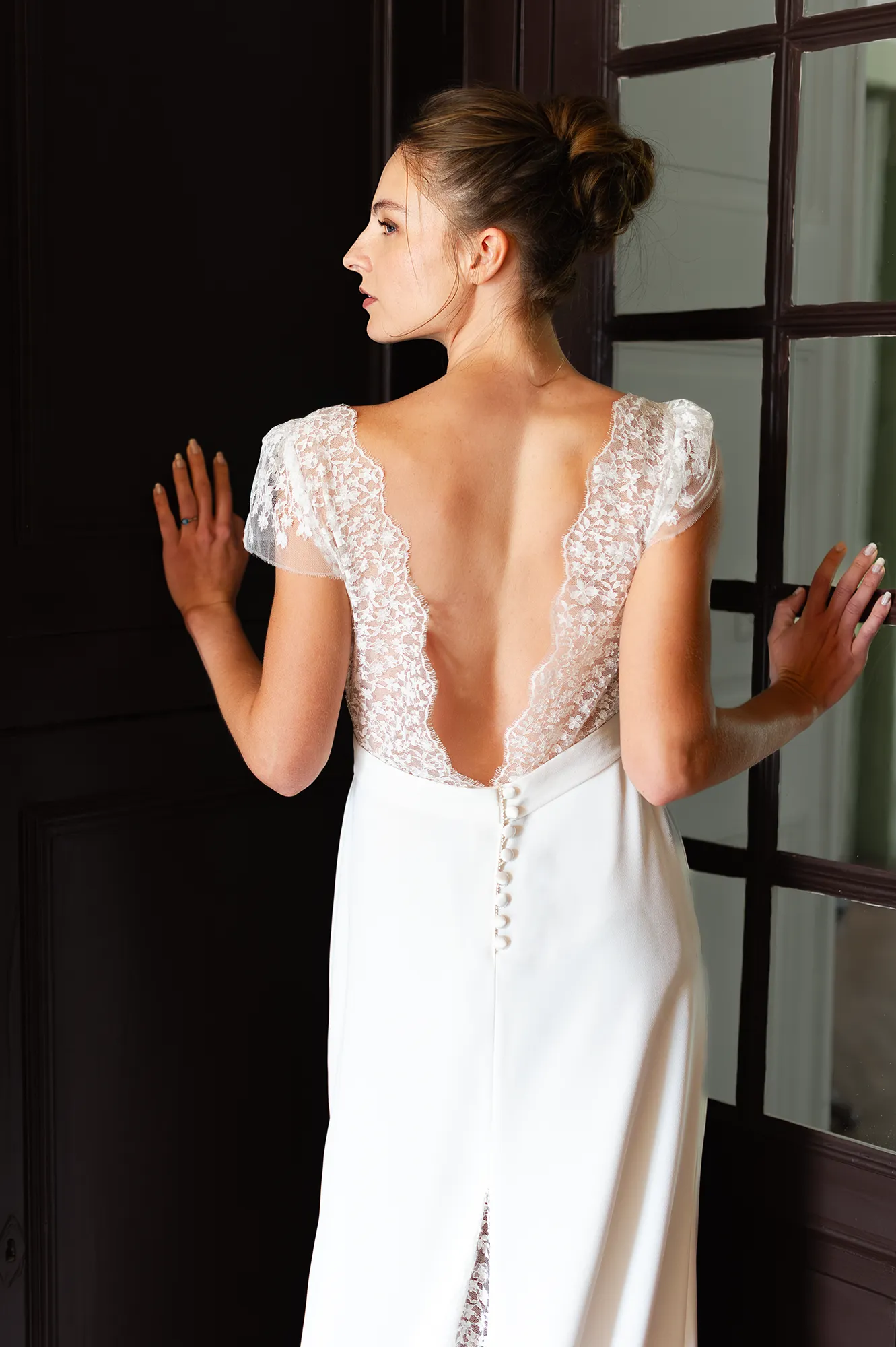 Robe de mariée Rebecca vue de dos, décolleté plongeant en dentelle de Calais-Caudry et boutonnage délicat. Création Louise Dentelle.