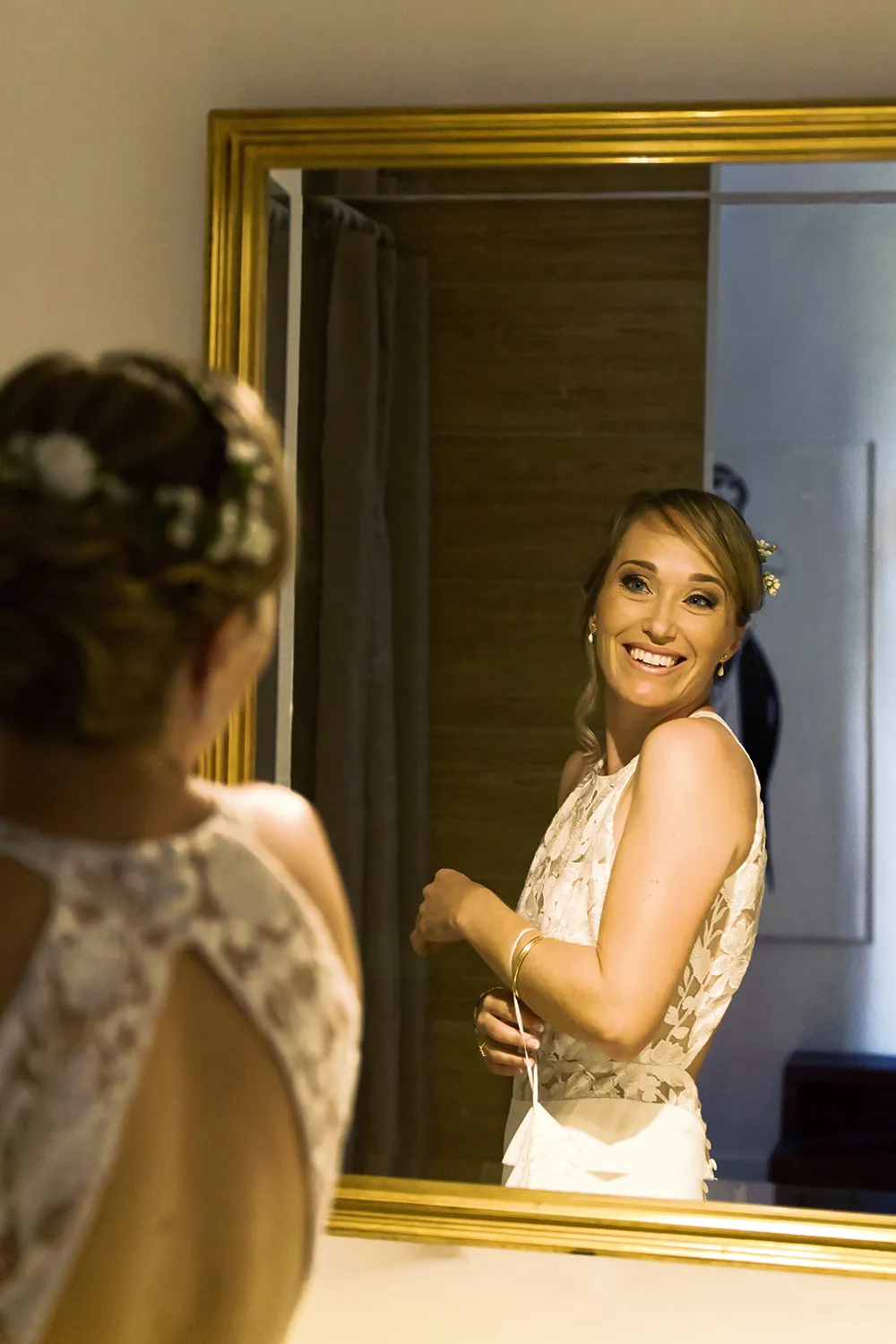 Cécile portant une robe de mariée sur mesure en dentelle devant un miroir création Louise Dentelle.