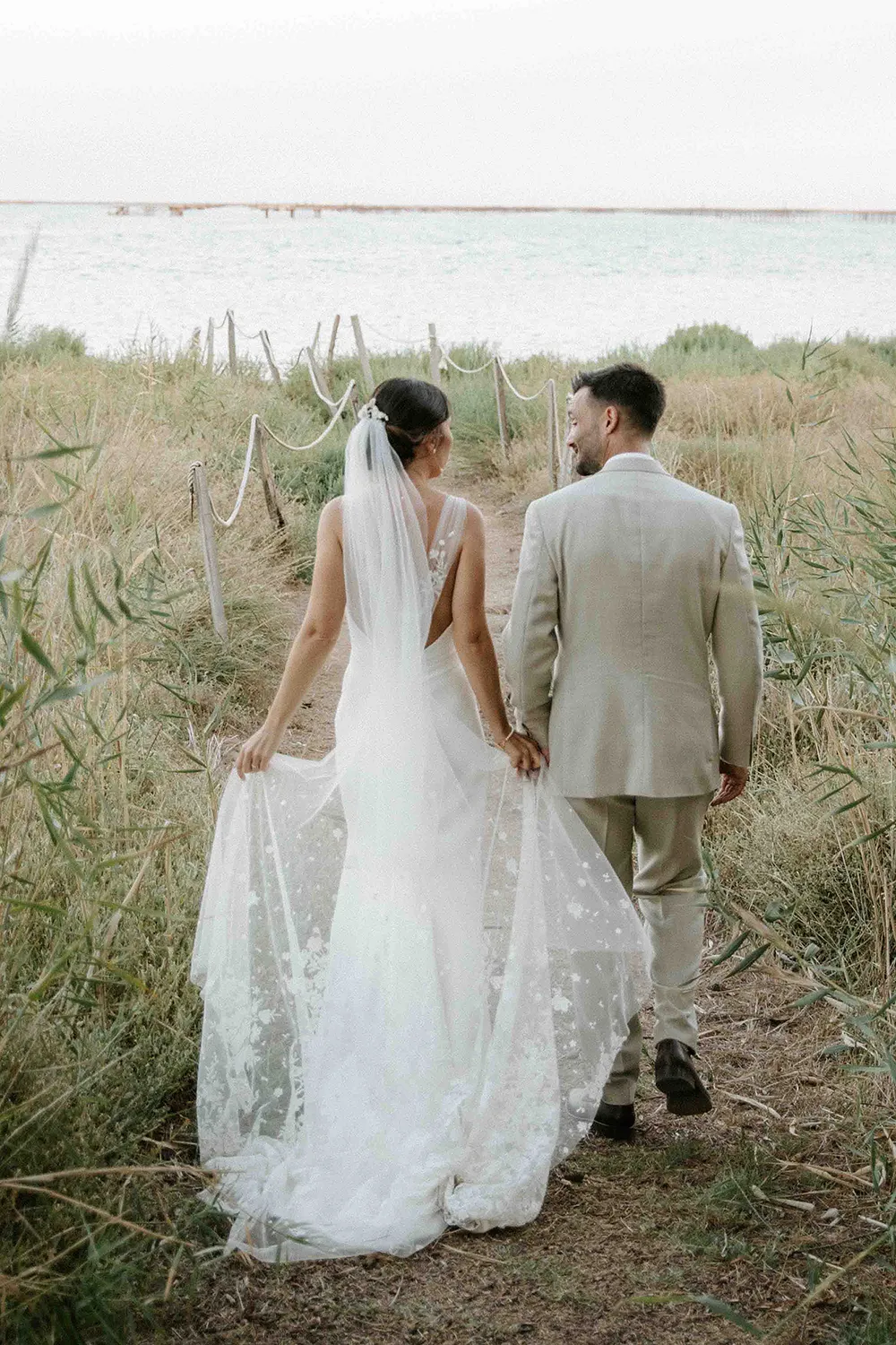 Laura portant une robe de mariée sur mesure en dentelle lors d’une promenade avec le marié création Louise Dentelle.